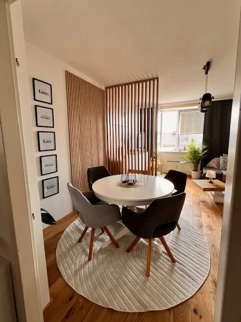 Essbereich mit rundem Tisch, dahinter Raumteiler aus Eichenlamellen zum Wohnzimmer, Kundenfoto