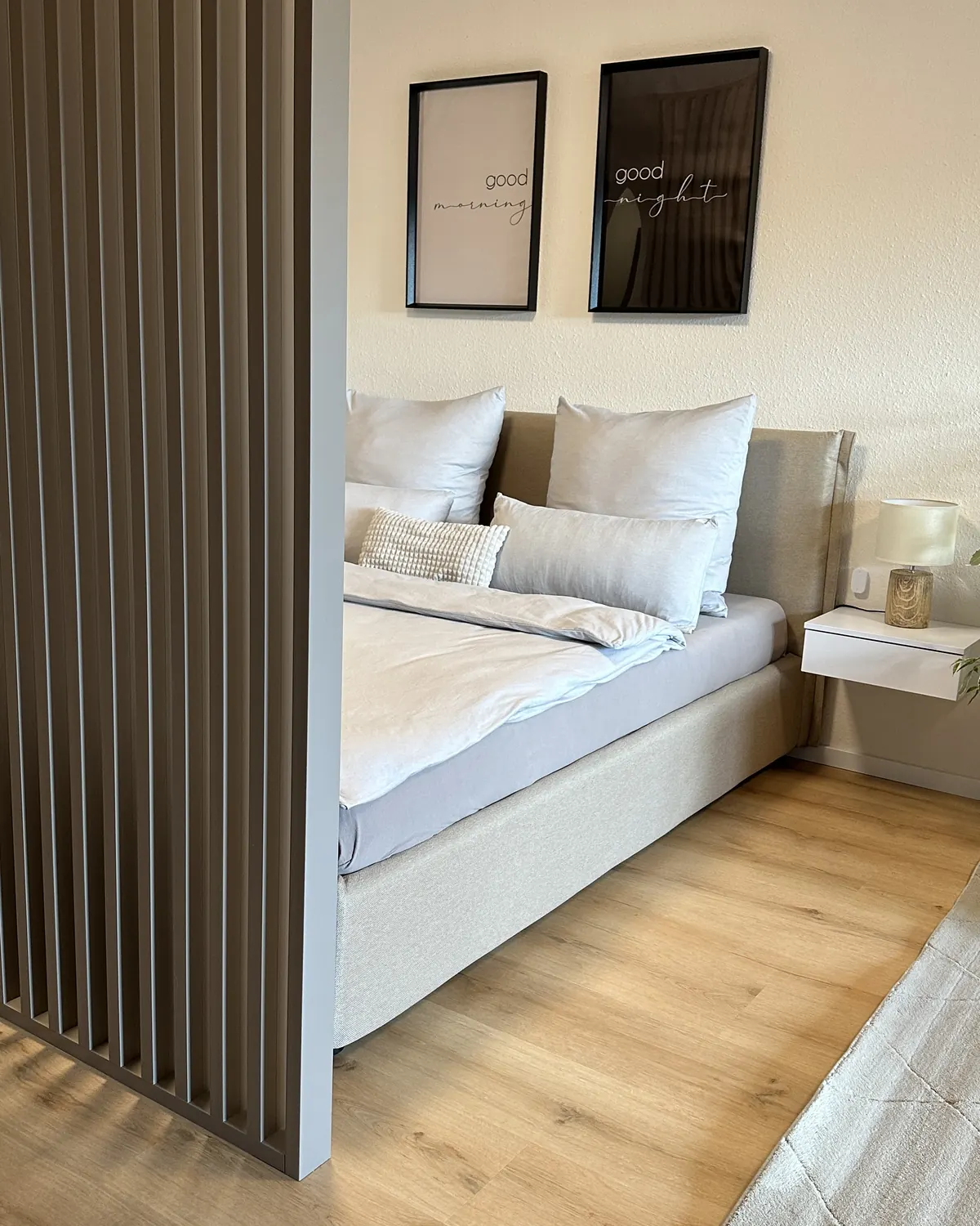 Raumteiler aus Holzlamellen vor dem Bett in einer Einzimmerwohnung, Kundenfoto